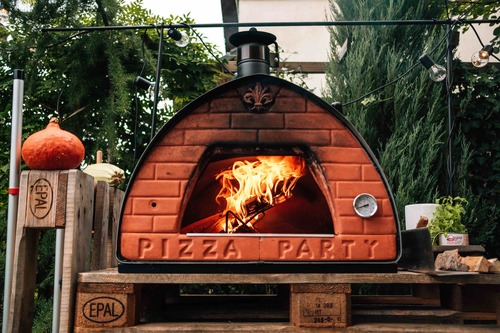 Domowa pizza pieczona a ogrodowym mobilnym piecu do pizzy opalanym drewnem